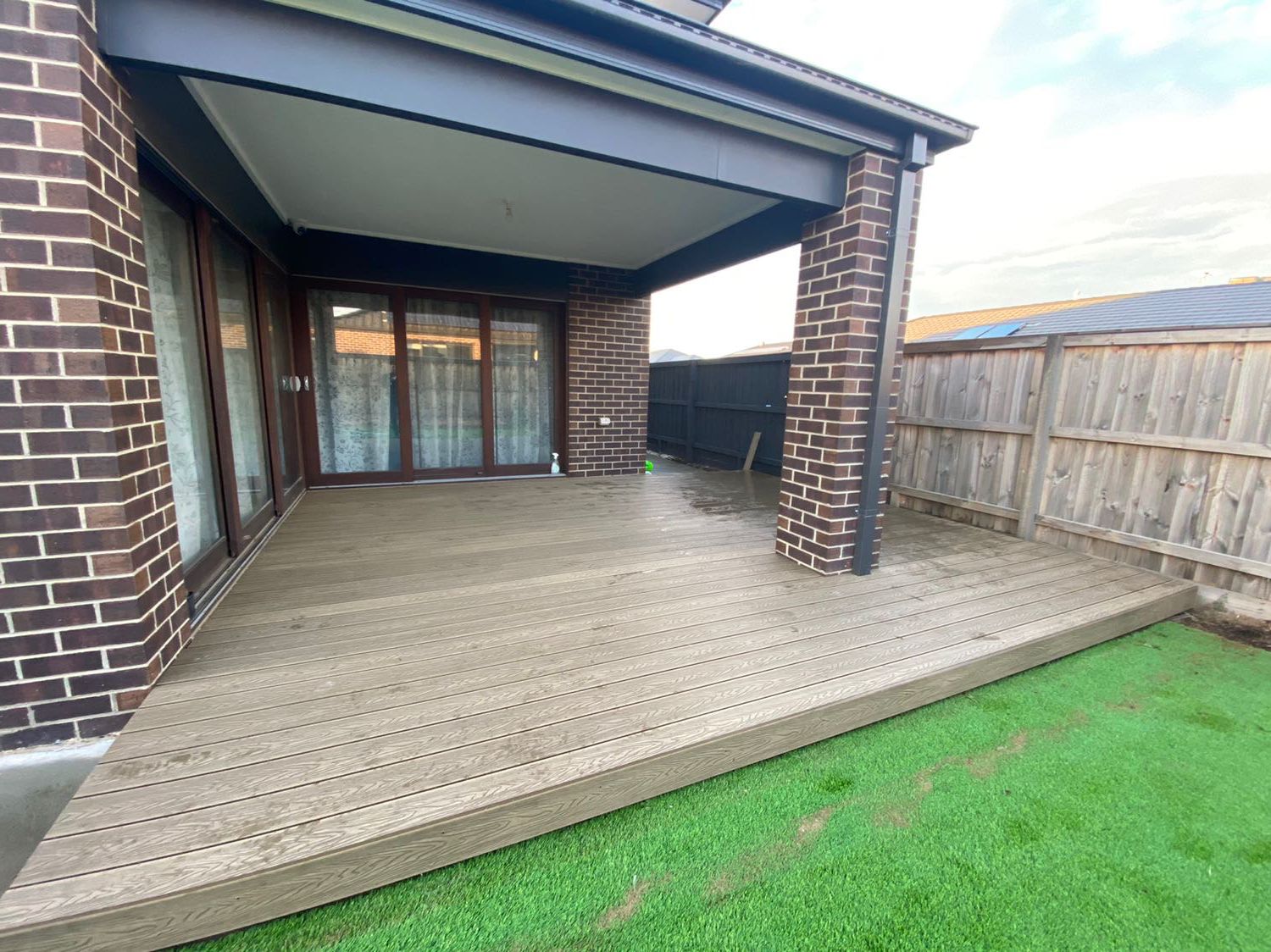 Light grey composite deck beside artificial lawn