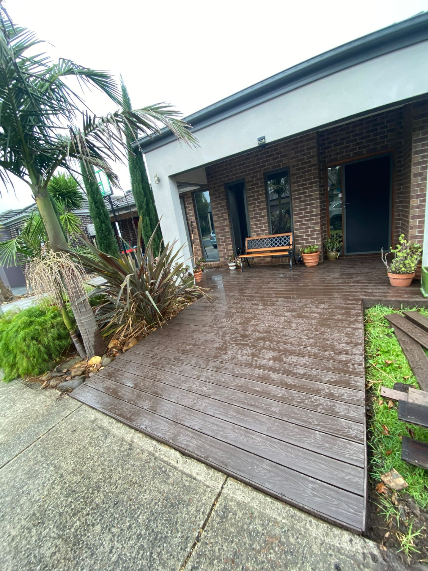 Front entry deck in dark composite boards with tropical planting