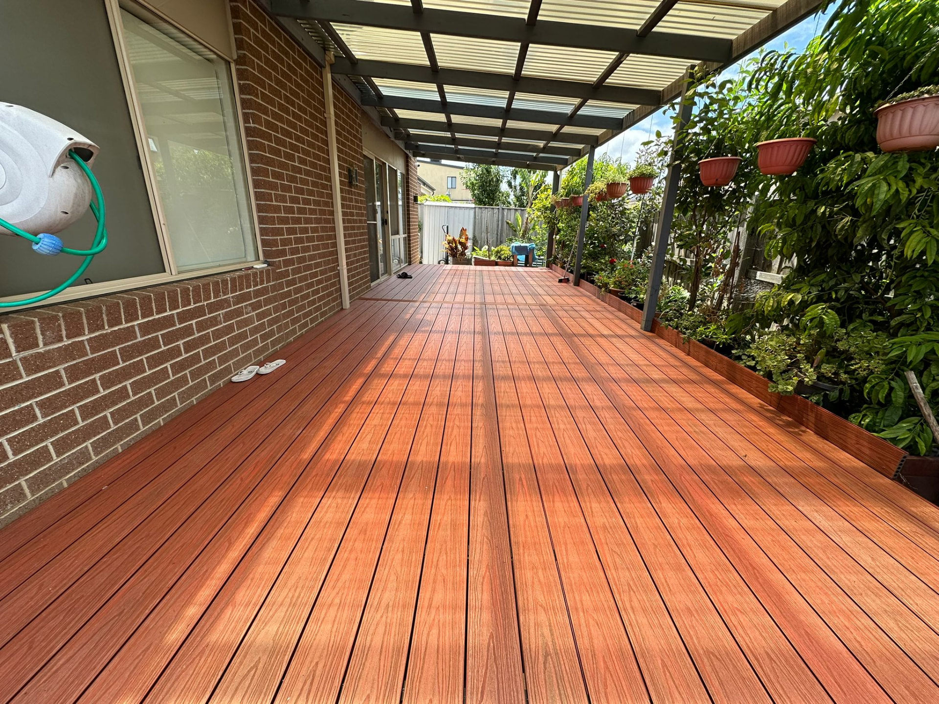 Long merbau toned deck under a pergola with hanging pots