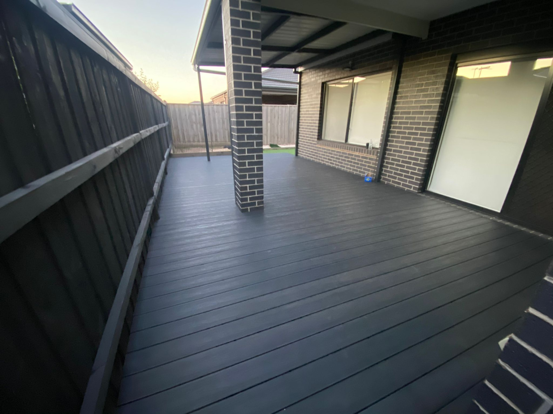 Charcoal composite deck wrapping around a modern brick house